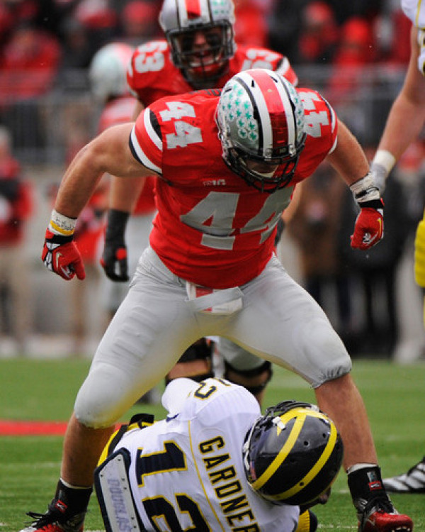 Ohio State's Boren, number 44, triumphantly stands over Michigan's Gardner, number 12, after a dominating play in the heated rivalry game.